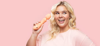 Woman with blonde hair smiling and holding up VUSH Majesty 2 wand vibrator