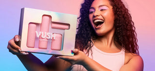 Woman with curly dark hair holding box with VUSH Pop Collection vibrators