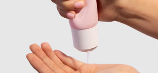 Right hand squeezing VUSH Intimate Gel in pink tube with white lid into left hand