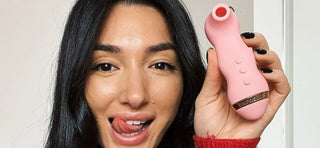 Ella Ding with black hair poking tongue out and holding VUSH Empress 2 vibrator
