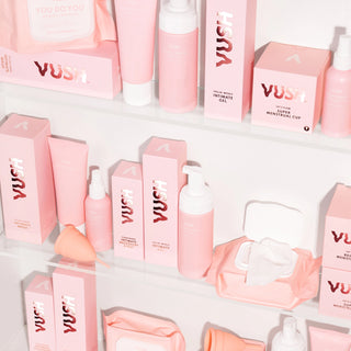 Bathroom cabinet fully stocked with VUSH Intimate Care Range. Products include intimate wipes, intimate gel (water-based lubricant), foaming intimate wash, and menstrual cup. All products are pink and white, some still in box packaging.